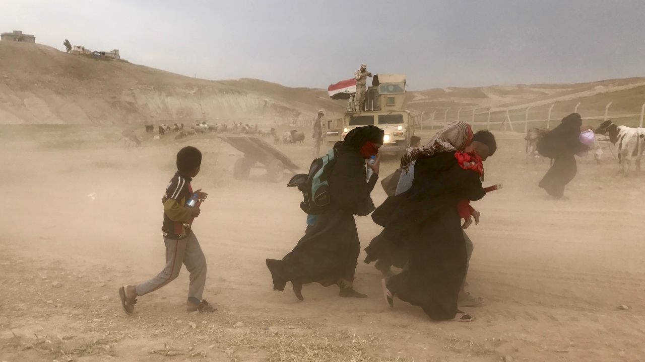 Residents from northwest Mosul flee fighting between Iraqi security forces and ISIS during a sandstorm carrying few belongings and their children in their arms.