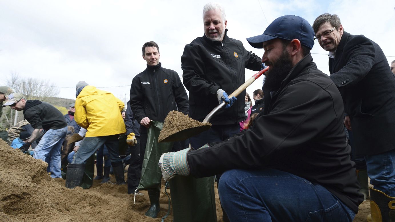 Quebec Premier Philippe Couillard uses a shovel to fill a sandbag as he tours a flood-affected area in Luskville, Quebec, on May 8.
