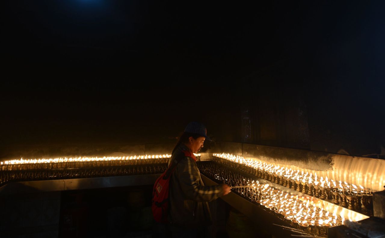 <strong>Nepal: </strong>A Nepalese Buddhist devotee lights oil lamps at a temple in Kathmandu. Buddha was born in Lumbini, Nepal some 125 miles southwest of the Kathmandu valley.  