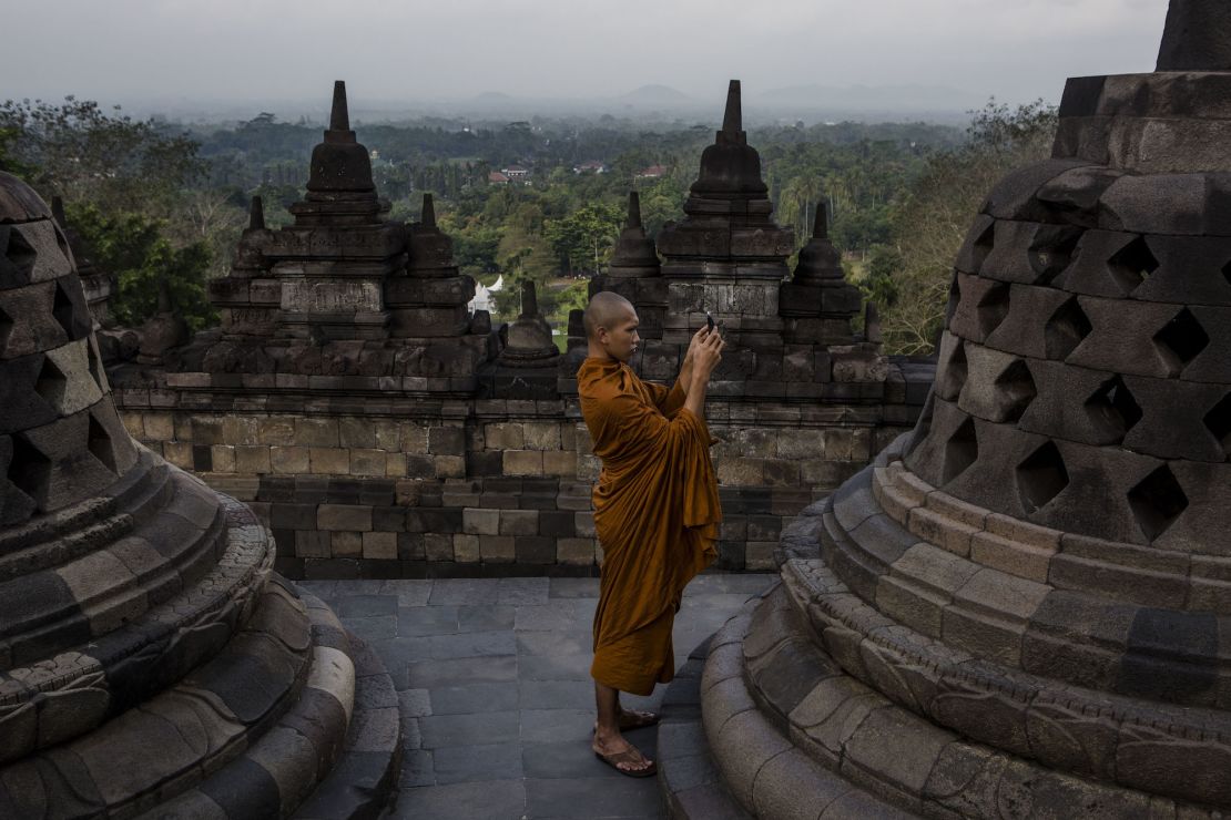 A Buddhist monk takes a picture of Buddha statue at Borobudur temple during celebrations for Vesak Day.