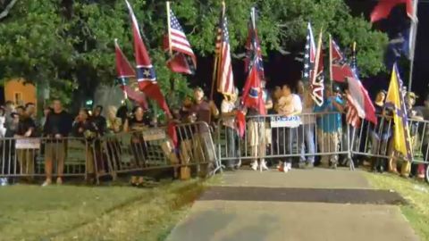 Those opposed to the Davis monument's removal wave Confederate and US flags Thursday morning.