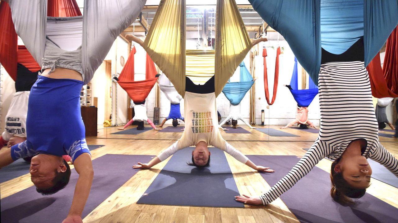 People enjoy aerial yoga using hammocks suspended from the ceiling in Tokyo. The trend is also called antigravity yoga. 