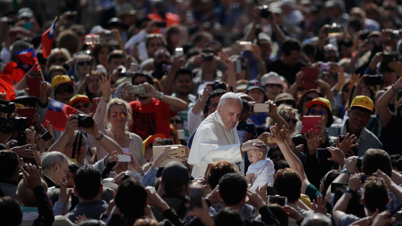 Pope Francis caresses a child's head Wednesday, May 10, as he arrives in St. Peter's Square at the Vatican.