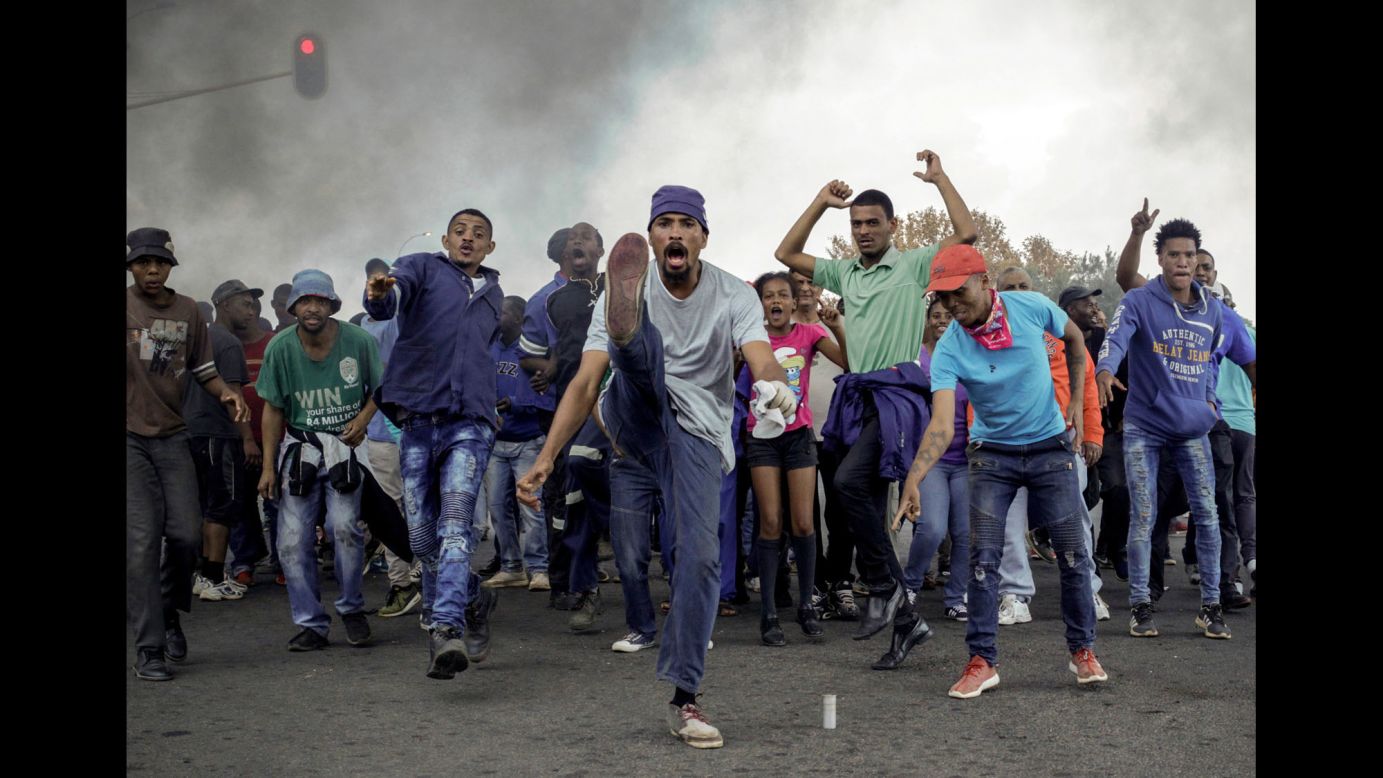 Protesters sing and chant in front of a burning barricade in Ennerdale, a Johannesburg suburb, on Tuesday, May 9. Violent protests over housing and government services erupted for a second day, with police firing rubber bullets at demonstrators who blocked roads and burned tires.