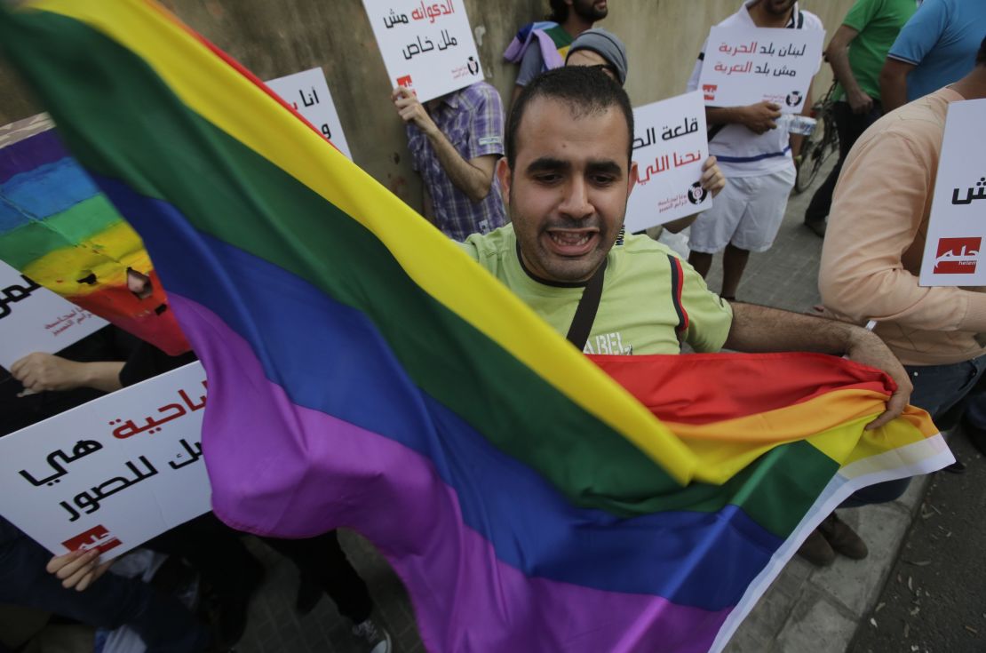 A protestor waves the gay pride flag as others hold banners during an anti-homophobia rally in Beirut on April 30, 2013.