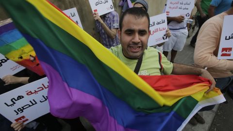 A protestor waves the gay pride flag as others hold banners during an anti-homophobia rally in Beirut on April 30, 2013.