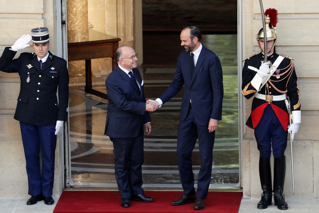 Newly appointed French Prime Minister Edouard Philippe, right, shakes hands with his predecessor, Bernard Cazeneuve, in Paris 