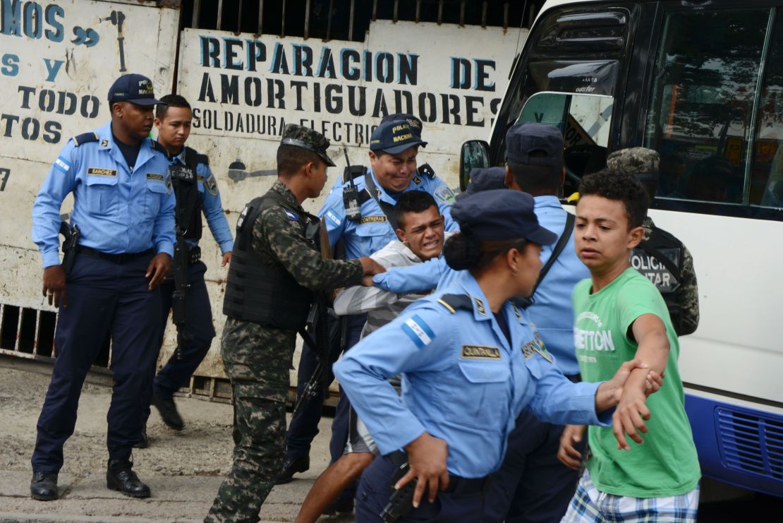 Police hold a boy whose father was killed in 2016 by alleged gang members for refusing to pay them a "war tax" in Tegucigalpa, Honduras.