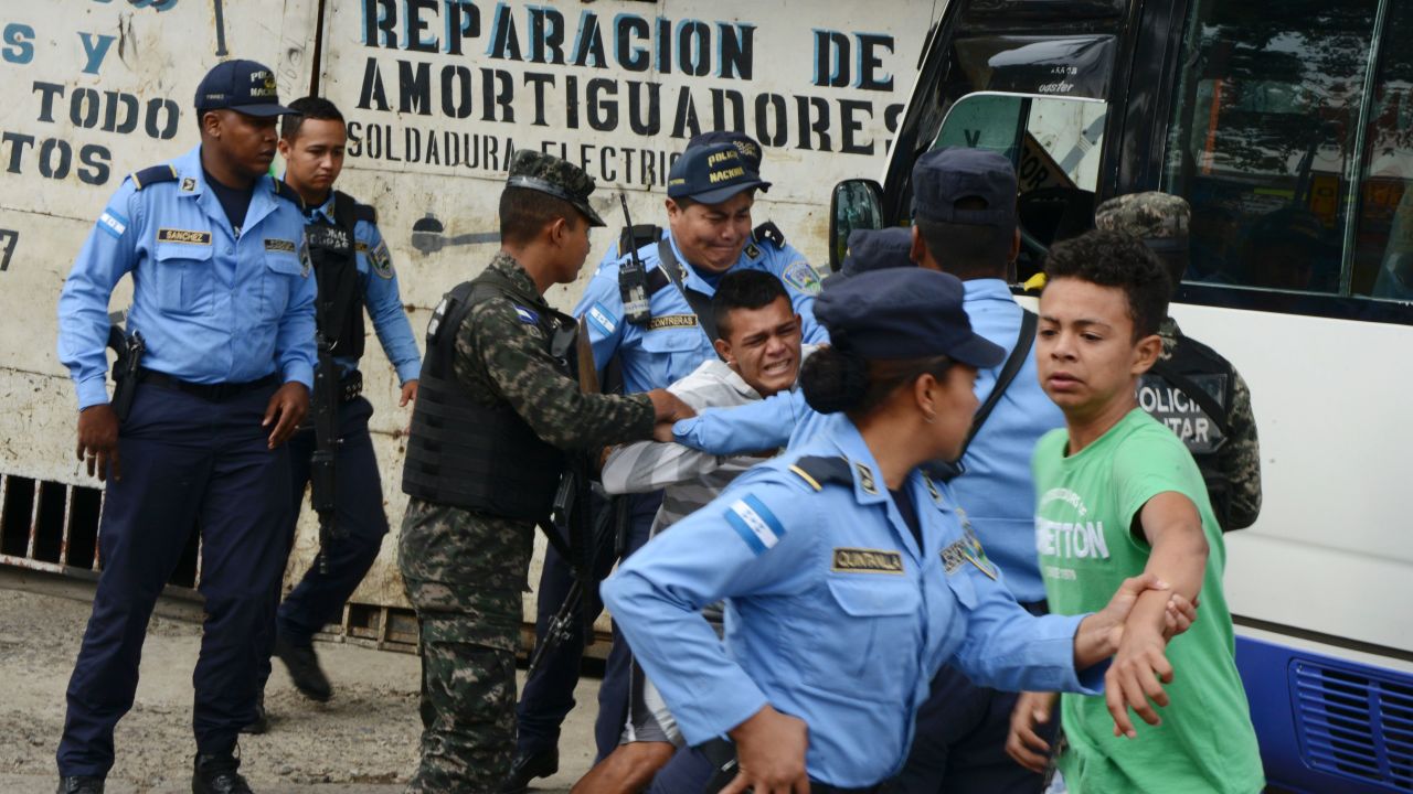Police hold a boy whose father was killed in 2016 by alleged gang members for refusing to pay them a "war tax" in Tegucigalpa, Honduras.