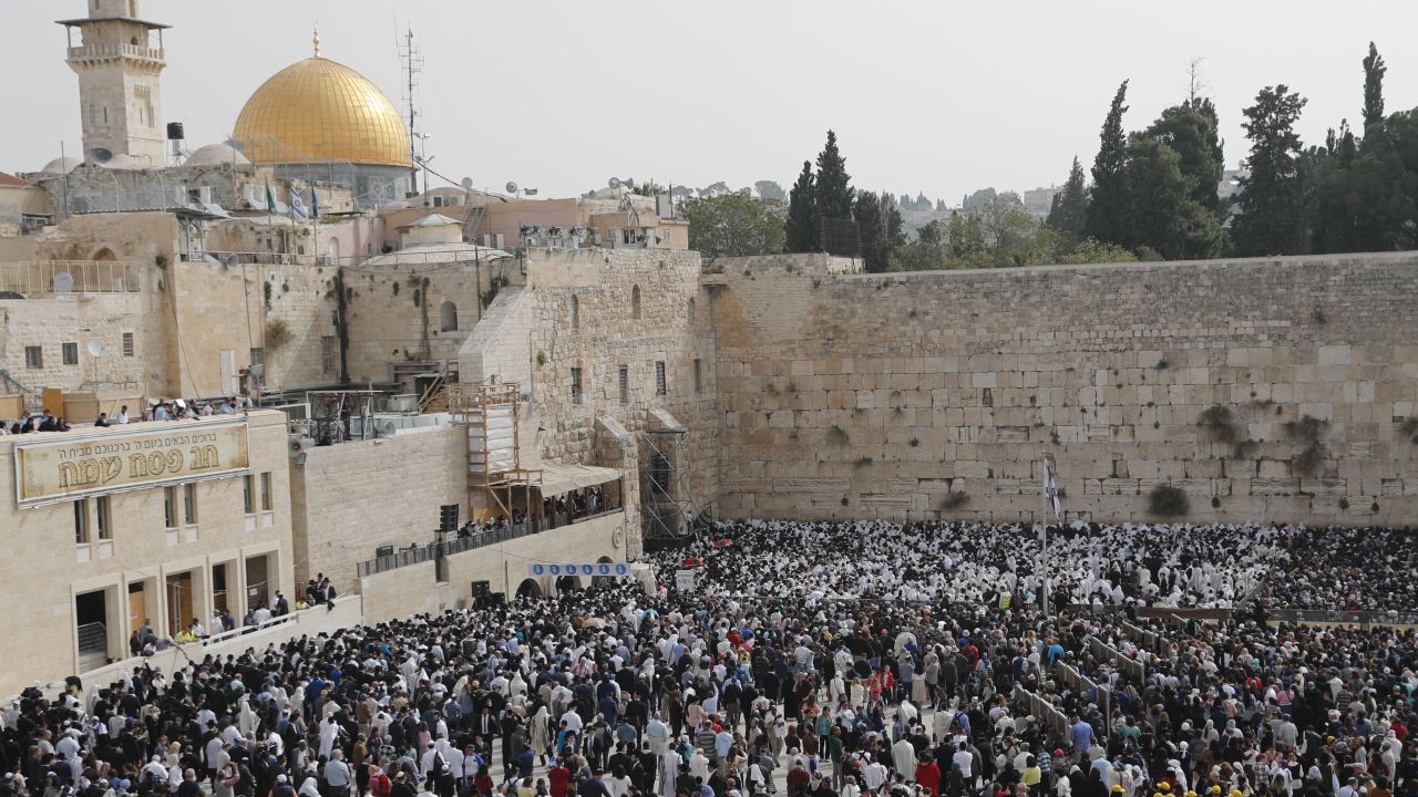 Jewish people take part in the Cohanim prayer (priest's blessing) during the Passover (Pesach) holiday at the Western Wall in the Old City of Jerusalem on April 13, 2017, with the Dome of the Rock seen in the background. 