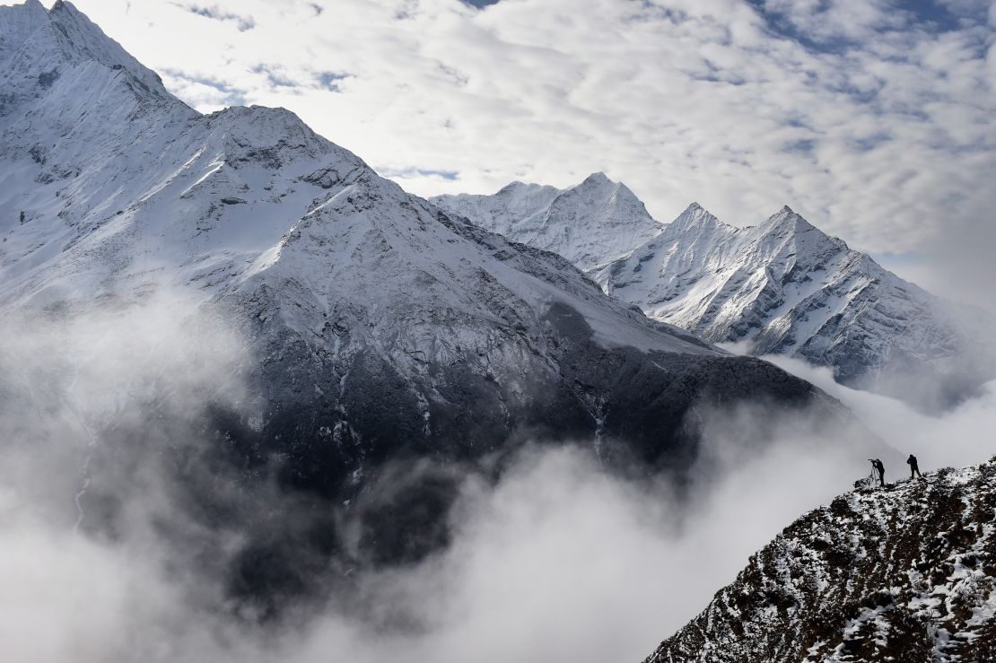 Climbers stand on a ridge over a valley leading north into the Khumbu region as they try to get a clear view of Mt. Everest, April 18, 2015.