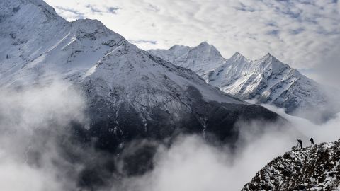 Climbers stand on a ridge over a valley leading north into the Khumbu region as they try to get a clear view of Mt. Everest, April 18, 2015.