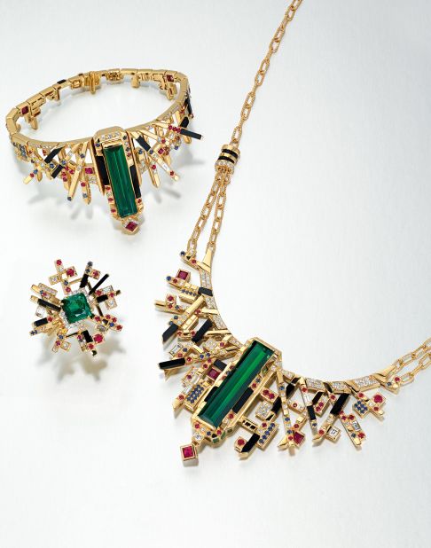 This jewelry set by Adrian Cheng comprises a neck chain, bracelet and ring centered on a striking green tourmaline, surround by onyx, rubies, sapphires and diamonds, mounted in gold.
