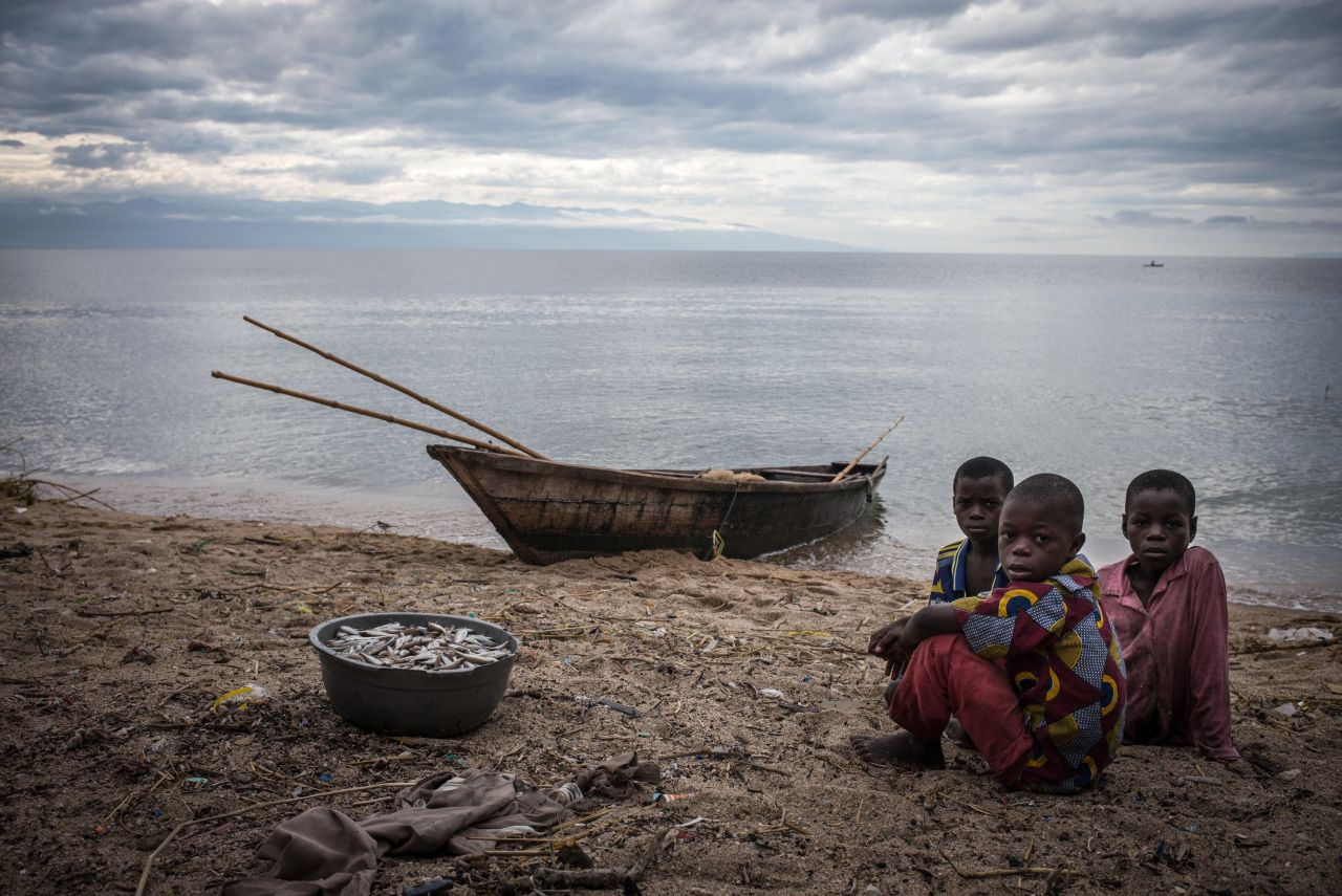 Children sit next to a bucket filled with fish on the shores of Lake Tanganyika in Uvira, Democratic Republic of Congo. One of Africa's Great Lakes, Tanganyika is the second largest in the continent, behind Lake Victoria. Bordering the DRC, Tanzania, Zambia and Burundi, the lives of millions living on its shores are under threat as the lake's ecosystem changes.
