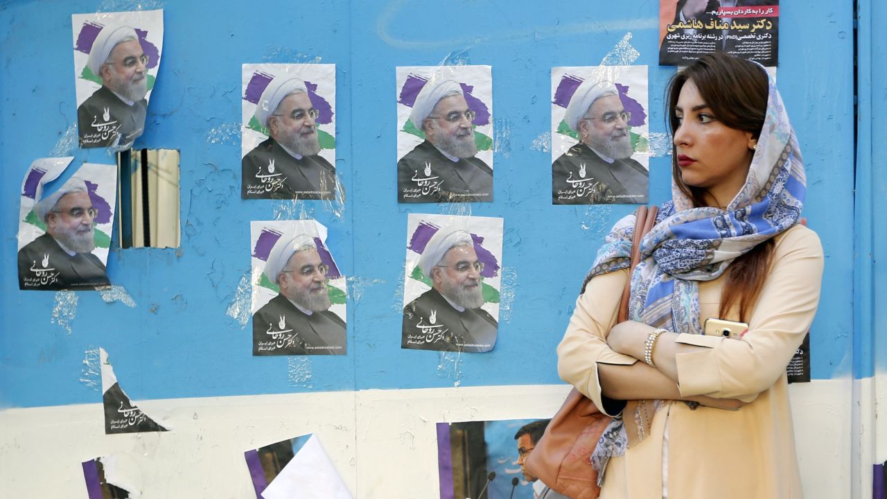 An Iranian woman stands next to a wall plastered with election posters of Iranian President and candidate Hassan Rouhani on a street in the capital Tehran on May 17, 2017.
Iran's presidential election on May 19 is effectively a choice between moderate incumbent Hassan Rouhani and hardline jurist Ebrahim Raisi, with major implications for everything from civil rights to relations with Washington. / AFP PHOTO / ATTA KENARE        (Photo credit should read ATTA KENARE/AFP/Getty Images)