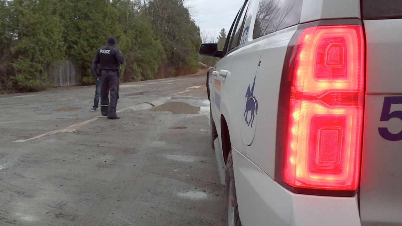 An officer with the Royal Canadian Mounted Police waits near the US-Canada border. Since January, police have registered more than 1,000 unauthorized border crossings from the United States into Canada on this street alone.