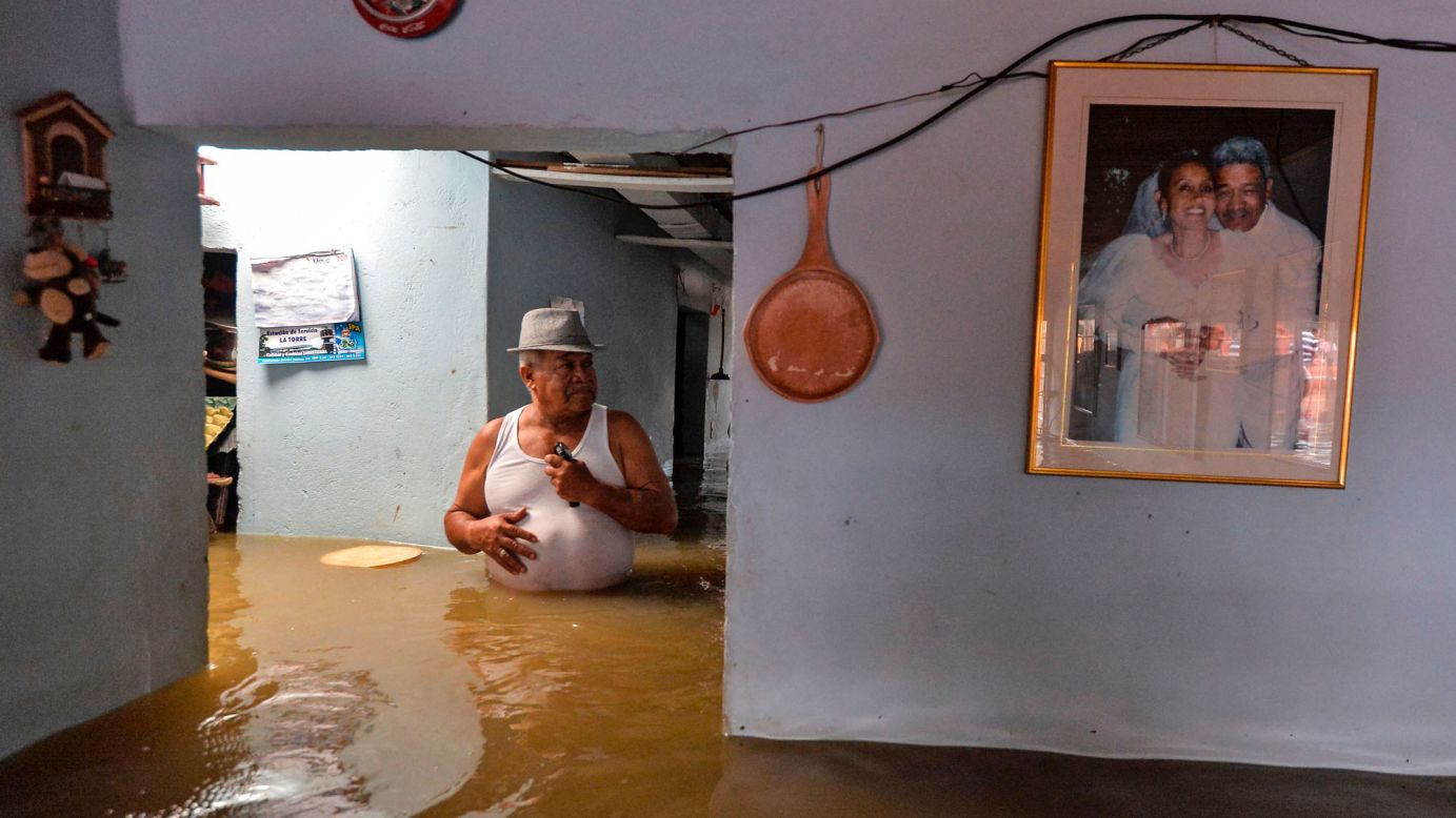 A man wades through his flooded home in Cali, Colombia, on Tuesday, May 16. Heavy rains cause the overflowing of the Cauca River.