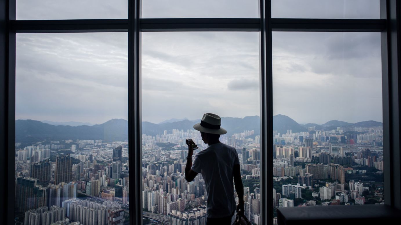 A visitor takes photos of Hong Kong's Kowloon district from the viewing deck of the International Commerce Centre on Tuesday, May 16.