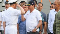 Philippine President Rodrigo Duterte (C) returns a salute from a Chinese naval officer (L) as Philippine Defence Secretary Delfin Lorenzana (R) looks on during Duterte's arrival to visit the guided missile frigate Changchun berthed at the Davao international port on May 1, 2017. 
Philippine President Rodrigo Duterte on May 1 visited Chinese warships docked in his home town and raised the prospect of future joint exercises, highlighting fast-warming relations despite competing claims in the South China Sea. / AFP PHOTO / MANMAN DEJETO        (Photo credit should read MANMAN DEJETO/AFP/Getty Images)