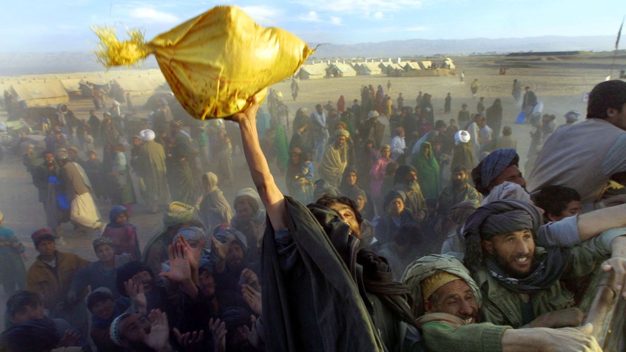 Afghan refugees reach for bags of rice and sugar being handed out by a local aid organization near Chaman, Pakistan, on December 4, 2001. Tens of thousands of Afghans had crossed the border since the 9/11 attacks.