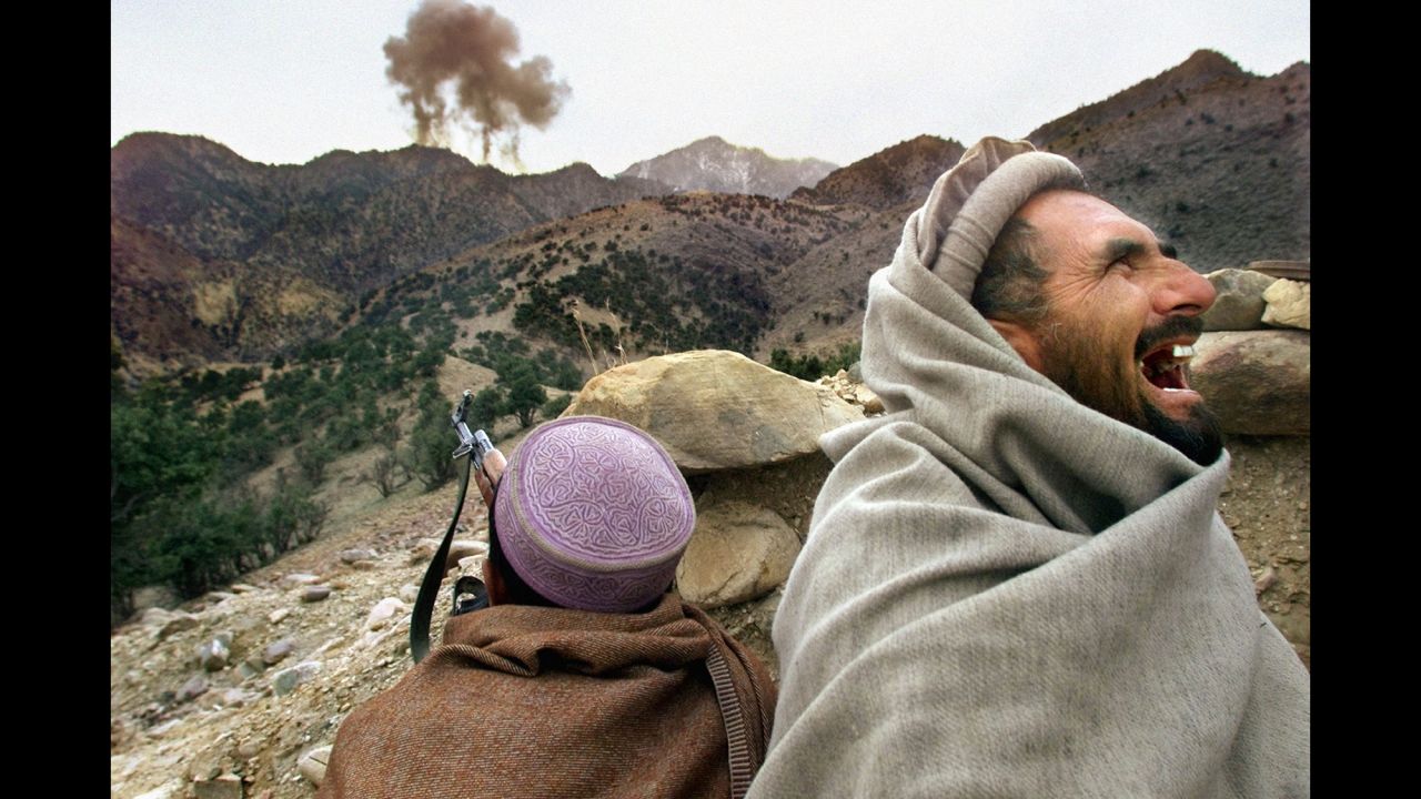 A Northern Alliance fighter bursts into laughter as US planes strike a Taliban position near Tora Bora, Afghanistan, in December 2001.