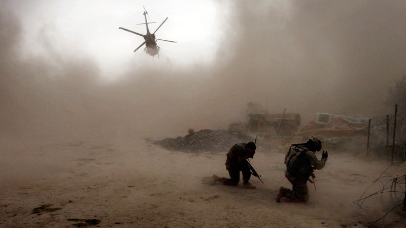 US soldiers shield themselves from dust as a helicopter takes off in Afghanistan's Arghandab Valley on July 30, 2010.