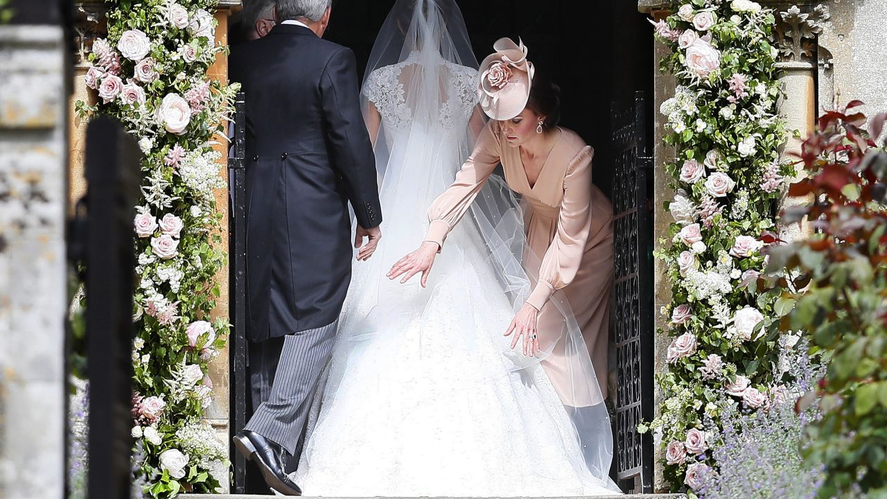 Catherine, Duchess of Cambridge, arranges the train of her sister Pippa Middleton's wedding dress.