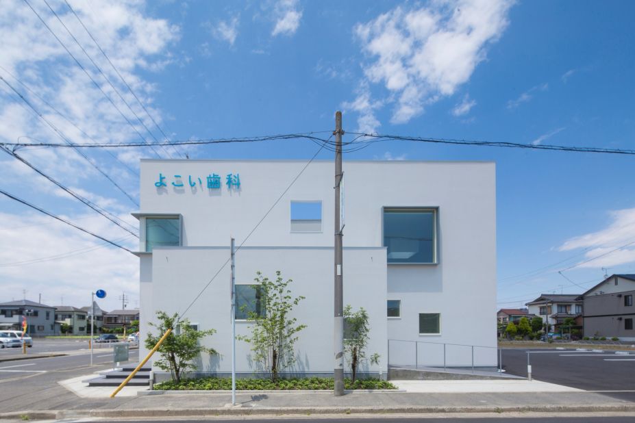 For a dental clinic in Japan, iks design and MASS Co created a white structure punctuated with square windows and skylights. Wooden beams with embedded lights warm up the consultation room.