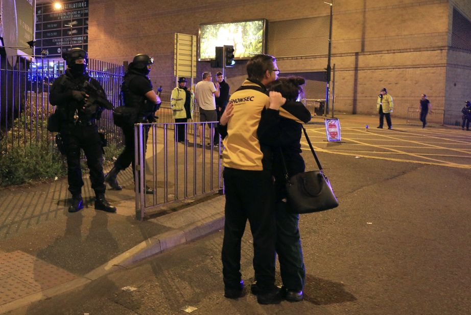 People hug near armed police who responded to the scene.