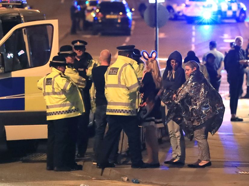 Emergency workers and concert attendees gather outside the arena.