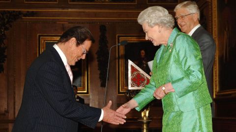 Moore is greeted by Britain's Queen Elizabeth II at Windsor Castle in 2006. In 2003, he was knighted for his charity work.