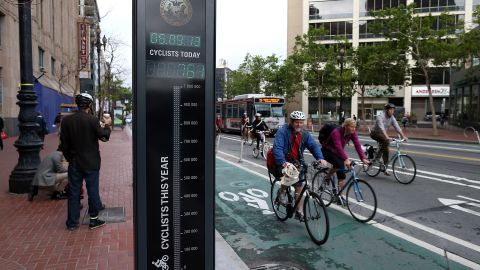 Bicyclists ride by an automated real-time bike counter in San Francisco, California.