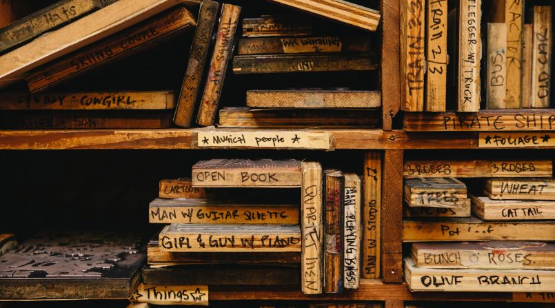 Imagery is carved into wooden blocks. The shop has a vast archive of blocks featuring images such as "man playing bass" and "girl & guy w/ piano."