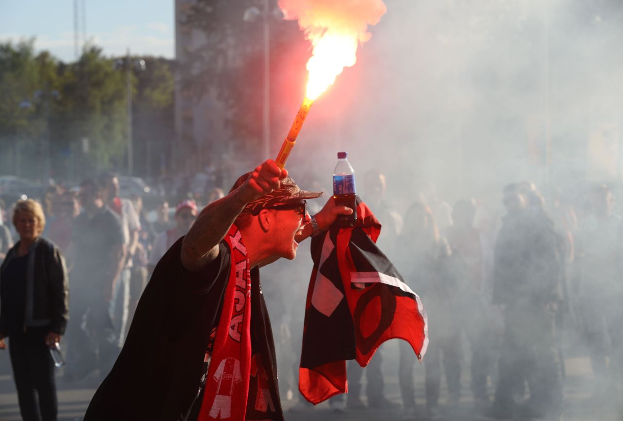 An Ajax supporter holds a lit flare prior to kick off.