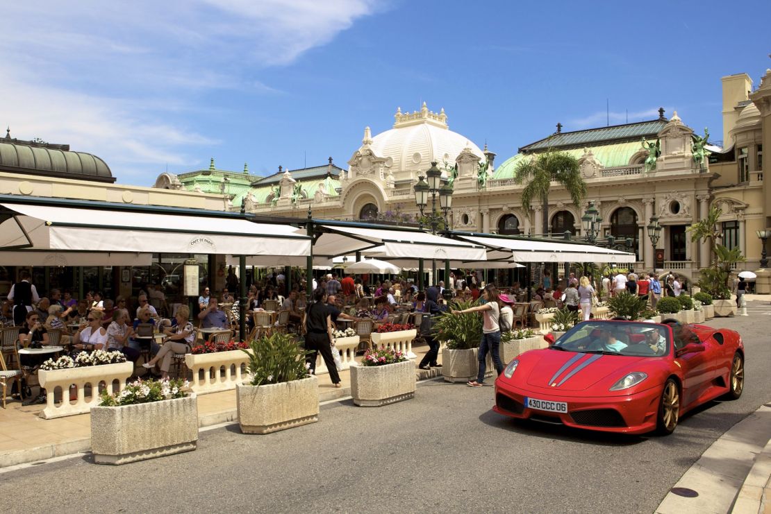 A Ferrari cabriolet drives by Monaco's Cafe de Paris terrace.
