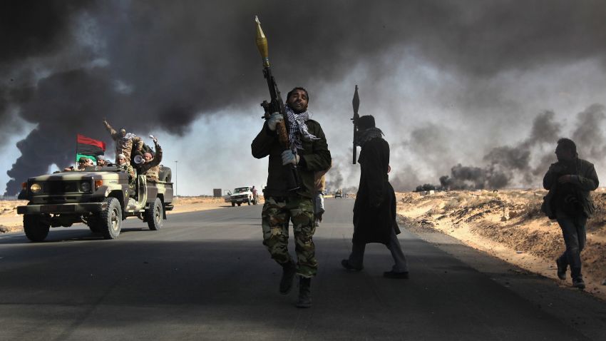 RAS LANUF, LIBYA - MARCH 11:  Libyan rebels battle government troops as smoke from a damaged oil facility darkens the frontline sky on March 11, 2011 in Ras Lanuf, Libya. Government troops loyal to Libyan leader Muammar Gaddafi drove opposition forces out of the strategic oil town, forcing a frantic rebel retreat through the desert.  (Photo by John Moore/Getty Images)