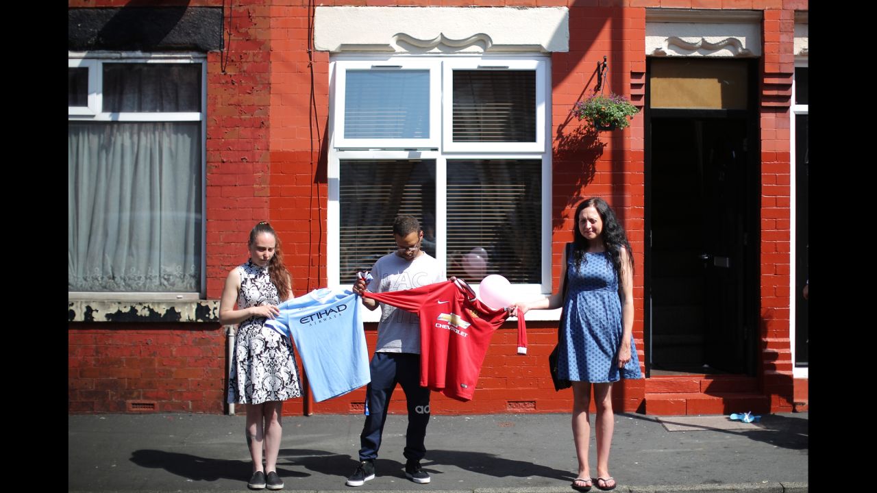 Local residents hold Manchester City and Manchester United soccer jerseys during the national minute of silence.