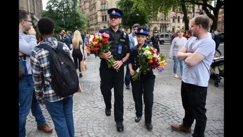 Police officers deliver flowers to a makeshift memorial in Manchester on Wednesday, May 24.