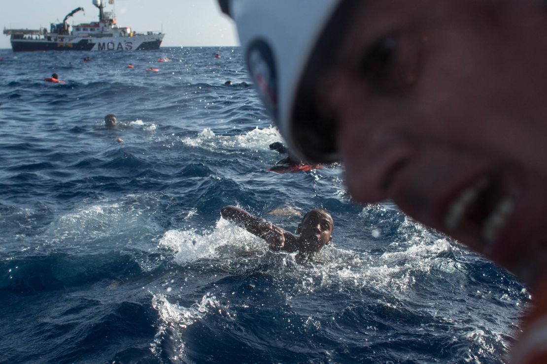 Refugees and migrants swim towards a rescue craft as a rescue crewmember from the Migrant Offshore Aid Station (MOAS) 'Phoenix' vessel pulls a man on board.