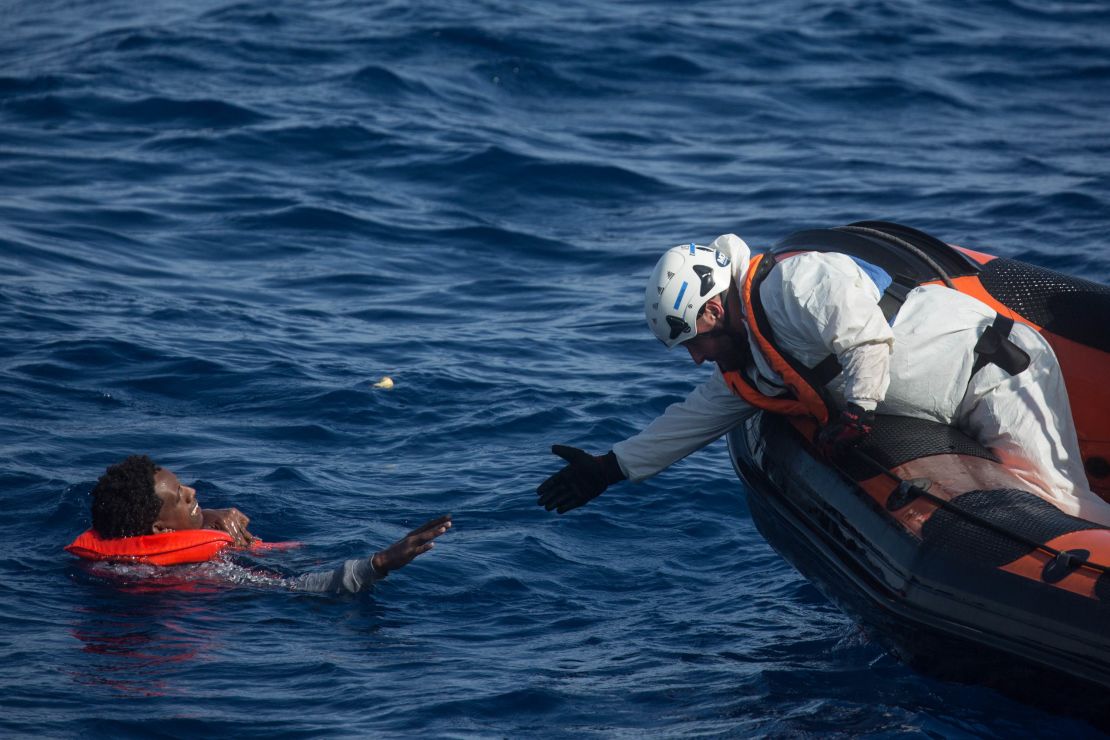 A rescue crewmember from the Migrant Offshore Aid Station "Phoenix" vessel reaches out to pull a man into a rescue craft on May 24.