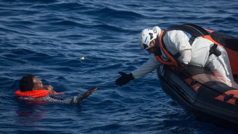 A rescue crewmember from the Migrant Offshore Aid Station "Phoenix" vessel reaches out to pull a man into a rescue craft on May 24.