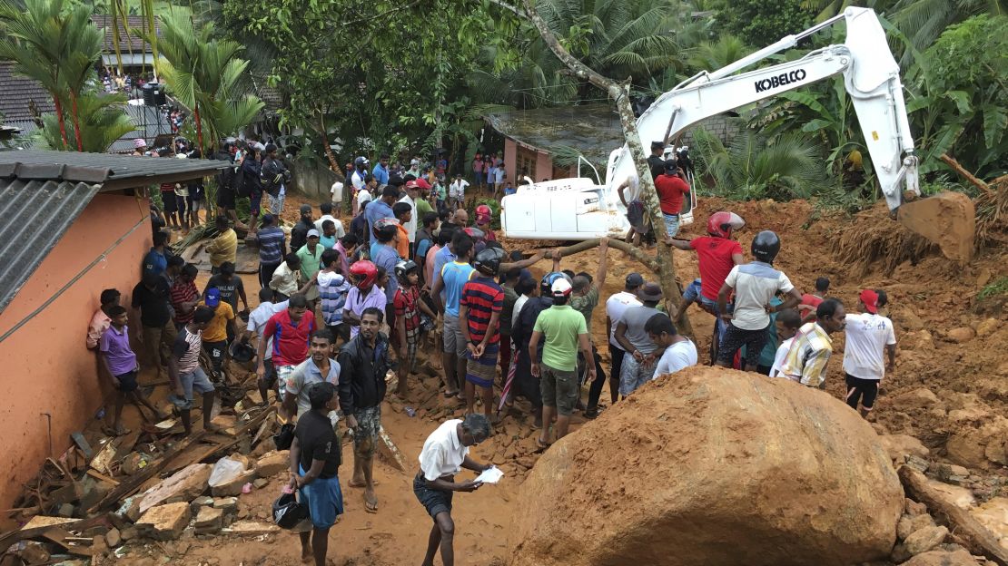 Residents watch a rescue operation in  Bellana village after monsoon rains caused landslides in the region.