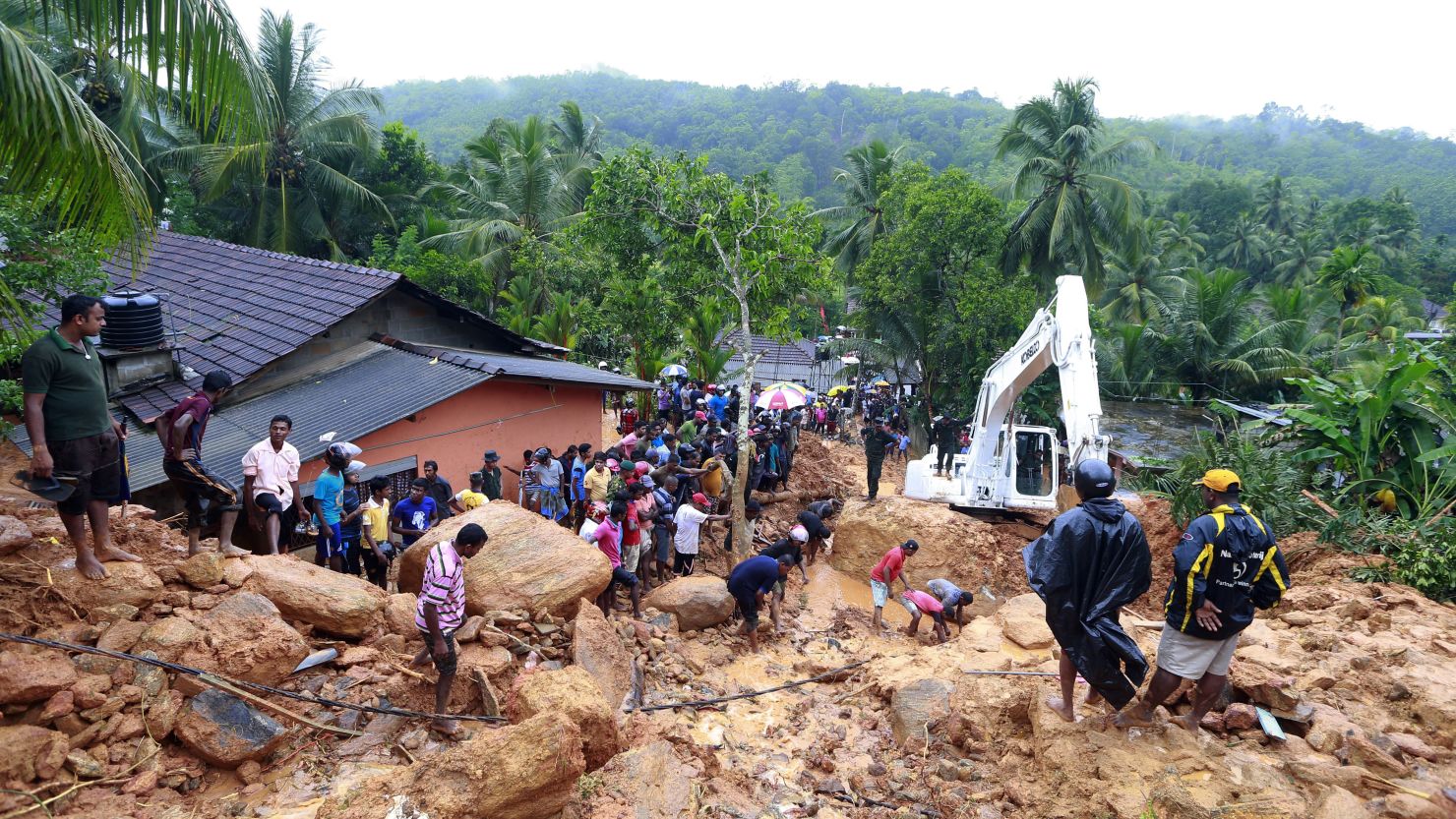 Residents of Bellana village in the Kalutara district watch as heavy machinery tries to move landslide debris on Friday, May 26, 2017