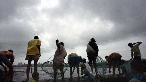 Indian men fish in the sea water in Mumbai.
