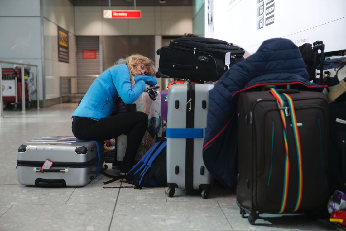 A traveller sleeps next to luggage at Heathrow Airport Terminal 5 after British Airways flights were canceled at Heathrow Airport.