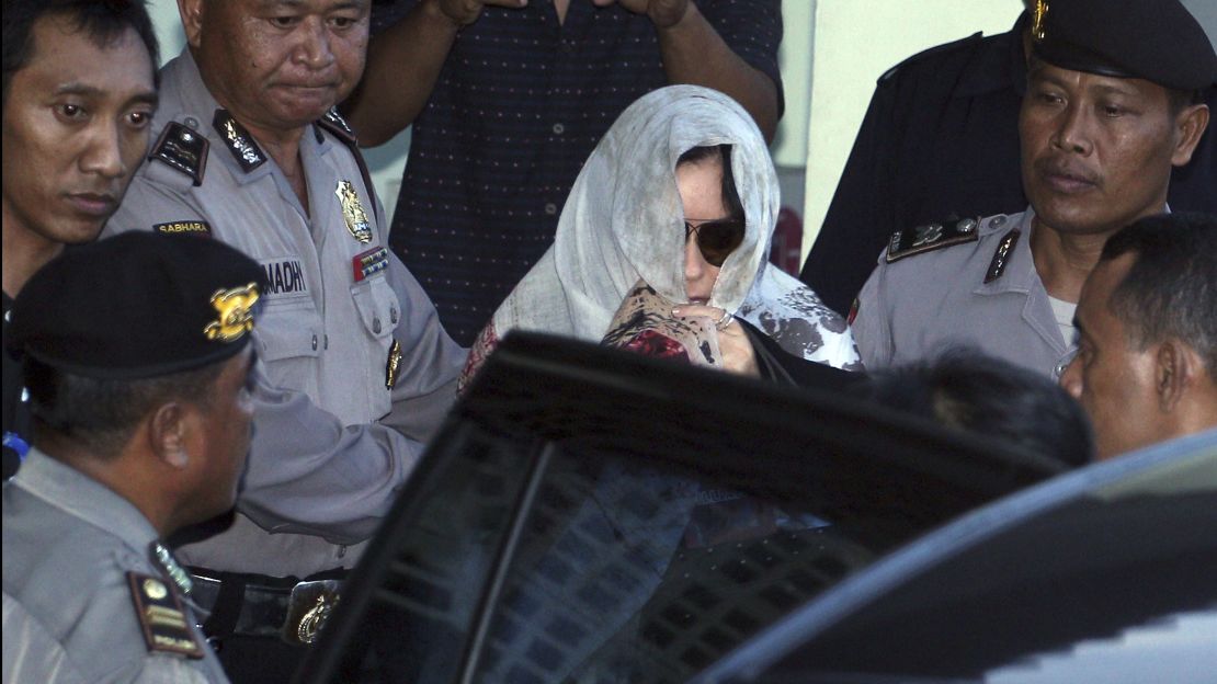  Schapelle Corby covers her head as she leaves the parole office in Bali, Indonesia, on Saturday.