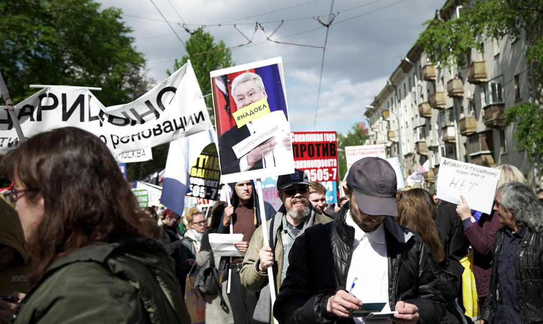 A protester holds a sign with an image of Mayor Sergei Sobyanin and the message: "We're tired of you."  