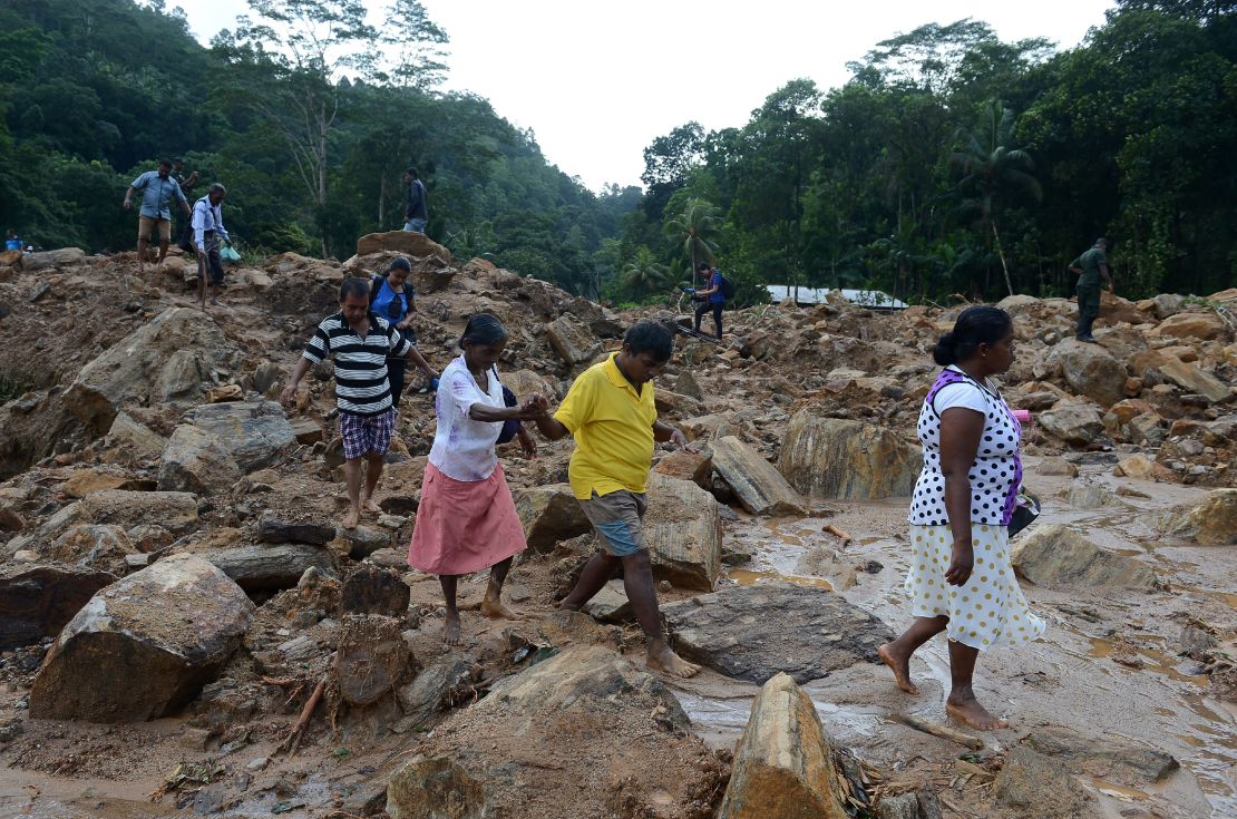 Sri Lankan villagers cross a landslide site as military rescue workers and villagers search for survivors in Athweltota village in Kalutara.
