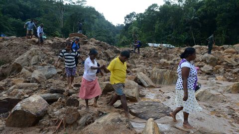 Sri Lankan villagers cross a landslide site as military rescue workers and villagers search for survivors in Athweltota village in Kalutara.