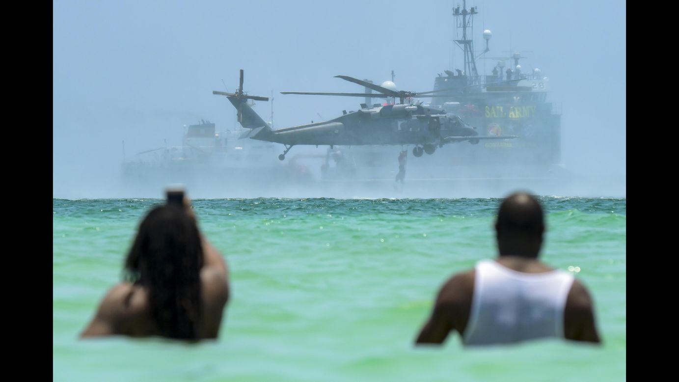 People wade in the water as they watch an air and sea show in Miami Beach, Florida, on Sunday, May 28. The demonstration involved military assets.